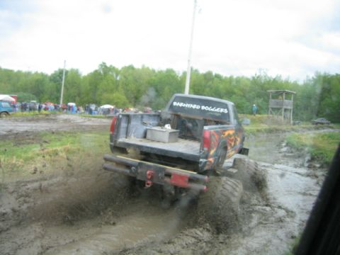 1978 Ford Bronco - A modified truck navigates a muddy track, kicking up spray as it goes.