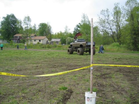 1978 Ford Bronco - A lifted truck with oversized tires sits in a muddy field, with houses and trees in the background.