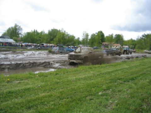 1978 Ford Bronco - Multiple trucks participate in a mud bogging event under a cloudy sky.