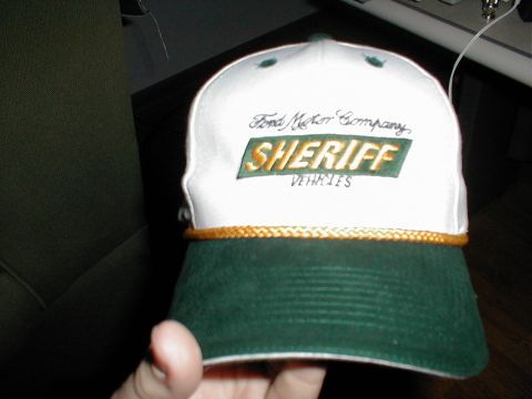 1999 Ford Crown Victoria - A baseball cap with "Sheriff Vehicles" embroidered on it is held up for the camera.