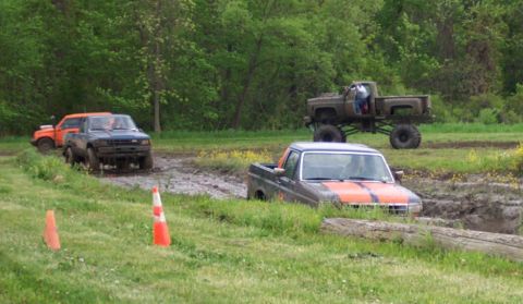 1978 Ford Bronco - Several trucks are stuck in a muddy off-road course during a mud bogging event.