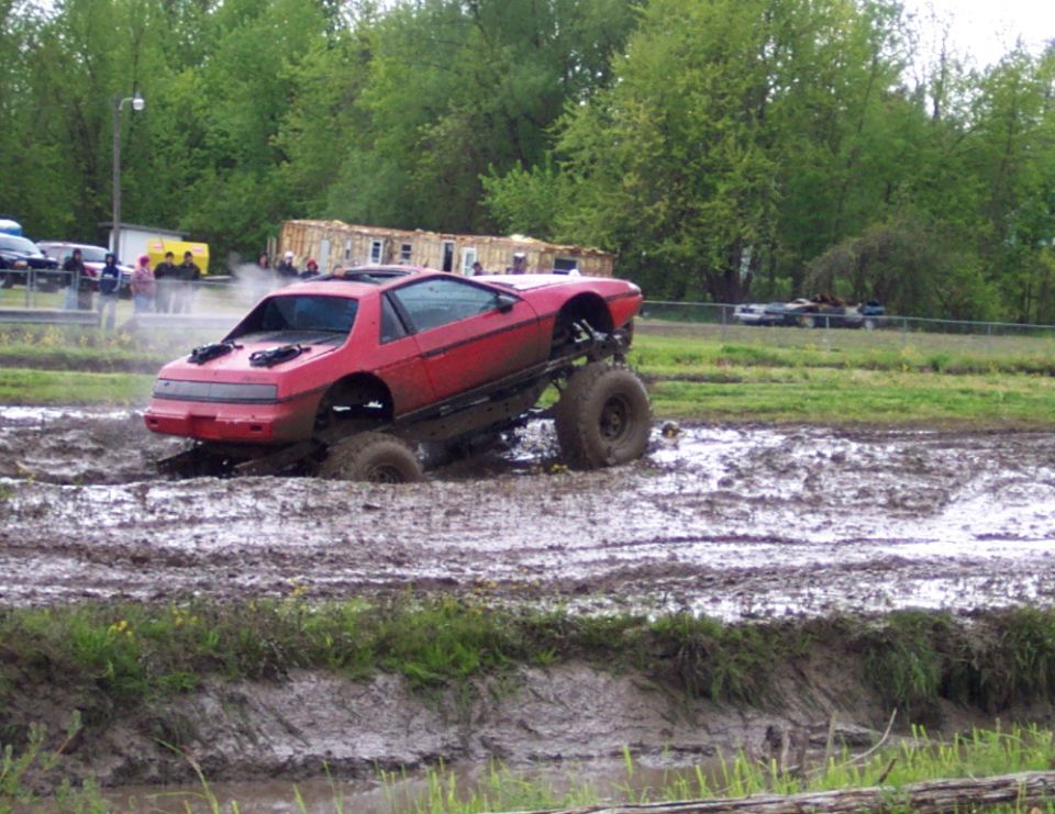 red Pontiac Fiero on huge tires stuck in mud
