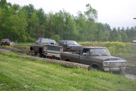 1978 Ford Bronco - Several trucks, including a 1978 Ford Bronco, are stuck in the mud during an off-road event.