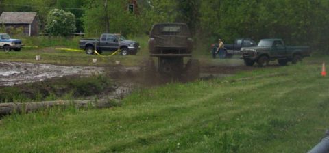 1978 Ford Bronco - Multiple trucks participate in a mud bogging event, kicking up mud and water.