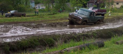 1978 Ford Bronco - Two trucks are stuck in a muddy track during what appears to be an off-road event.