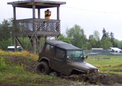 1978 Ford Bronco - A Jeep Wrangler is stuck in the mud, with a person in a yellow jacket in an observation tower above.