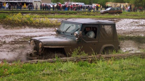 1978 Ford Bronco - Jeep CJ-7 navigates a challenging muddy terrain during an off-road event.
