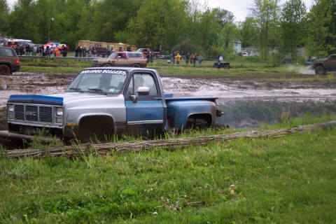 1978 Ford Bronco - A GMC pickup truck navigates a muddy course, with "BARNYARD BOGGERS" visible on the driver's side door.