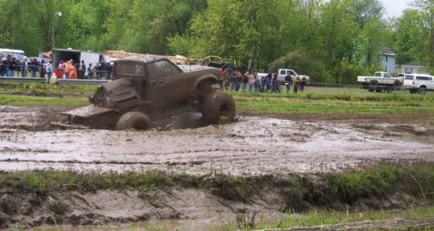 1978 Ford Bronco - A modified truck is stuck deep in the mud during a competition, with spectators gathered nearby.