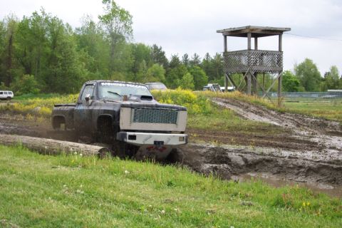 1978 Ford Bronco - A modified pickup truck navigates a muddy track, with a wooden tower overlooking the course.