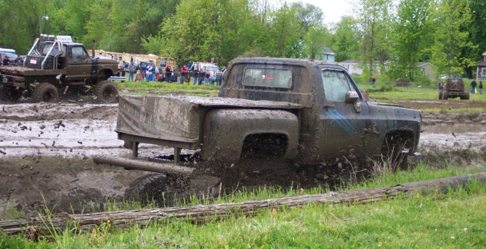 Mud-splattered pickup truck in a mud bog, side view