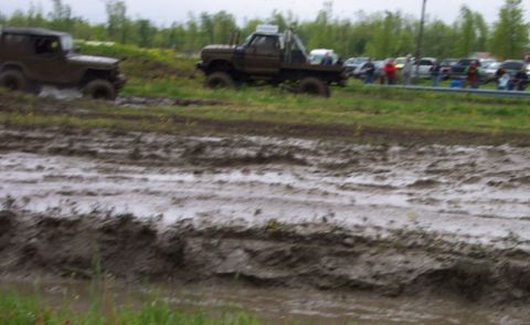 1978 Ford Bronco - Off-road vehicles navigate a challenging mud course with onlookers watching.