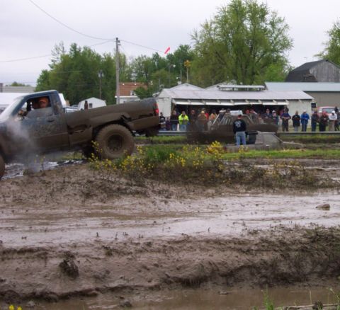 1978 Ford Bronco - A pickup truck navigates a challenging mud course, with onlookers gathered to watch the event.
