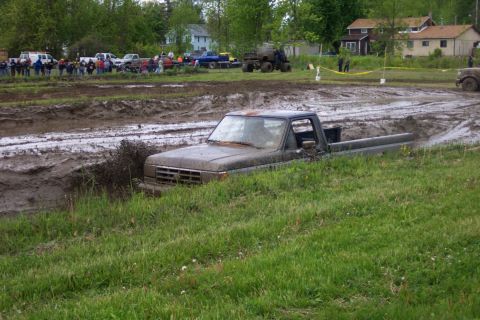 1978 Ford Bronco - A truck is stuck in the mud during an event, with spectators gathered around.