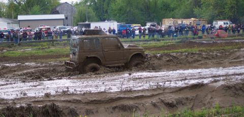 1978 Ford Bronco - An off-road vehicle is stuck deep in the mud during a competition, with a crowd observing the event.