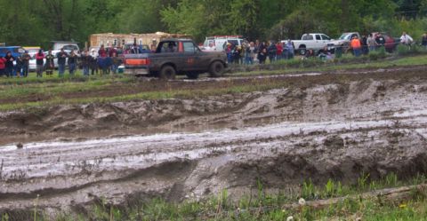 1978 Ford Bronco - Spectators watch trucks navigate a muddy track during a mud bogging event.