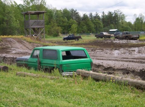 1978 Ford Bronco - A green 1978 Ford Bronco is stuck in a muddy track, with other trucks in the background.