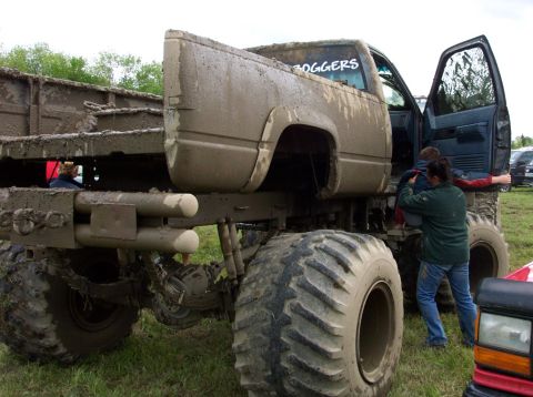 1978 Ford Bronco - A heavily mud-splattered pickup truck with oversized tires is shown, with people entering the cab.