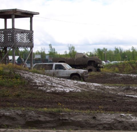 1978 Ford Bronco - Two off-road vehicles are stuck in the mud near a wooden tower.