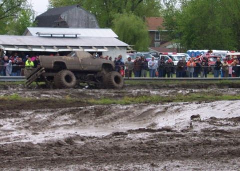 1978 Ford Bronco - A monster truck navigates a muddy course with spectators observing the event.