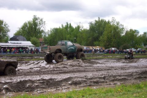 1978 Ford Bronco - Modified trucks compete in a mud bogging event with spectators watching from the sidelines.