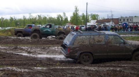 1978 Ford Bronco - Multiple off-road vehicles covered in mud during a competition event.