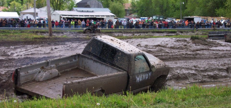 Mud-covered pickup truck stuck in mud pit with 'WENDY' written on door