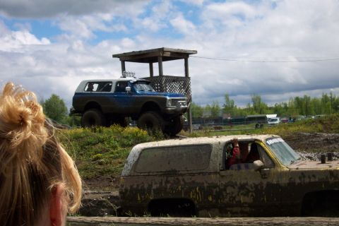 1978 Ford Bronco - Two SUVs are participating in an off-road event, covered in mud under a cloudy sky.