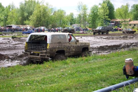 1978 Ford Bronco - A muddy SUV navigates a challenging mud pit during an off-road event.