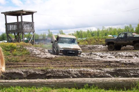 1978 Ford Bronco - A light blue pickup truck is stuck in a mud pit, with another dark-colored truck visible in the background.