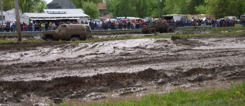 1978 Ford Bronco - Off-road vehicles compete in a mud bogging event with spectators lining the track.
