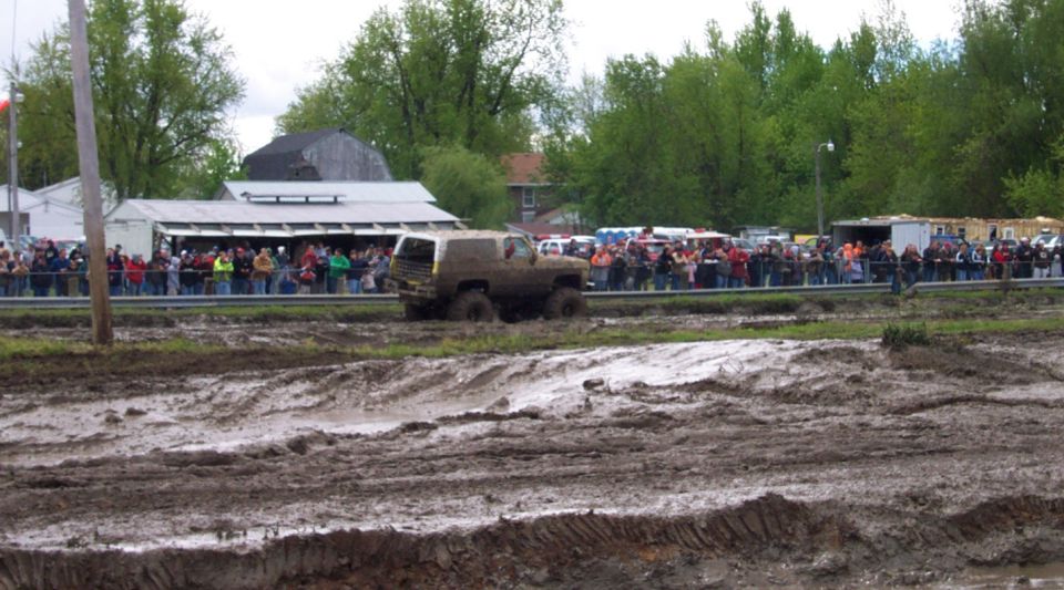 1978 Ford Bronco driving through mud pit with crowd watching