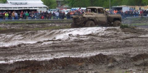 1978 Ford Bronco - A heavily modified truck navigates a challenging mud course, kicking up dirt and water for onlookers.