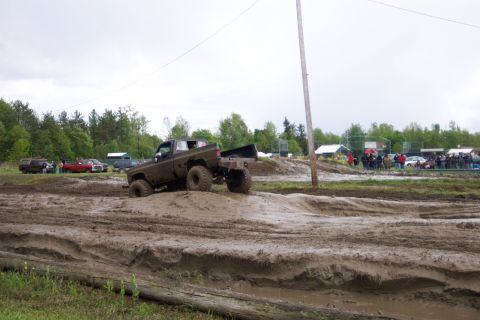 1978 Ford Bronco - A lifted pickup truck navigates a challenging mud course during an outdoor event.