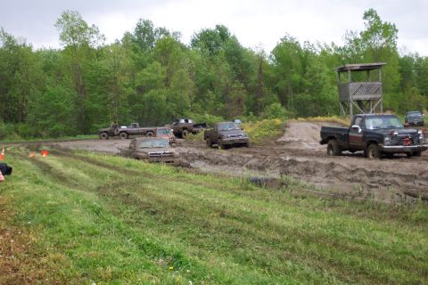 1978 Ford Bronco - Multiple trucks navigate a challenging mud course under an overcast sky.