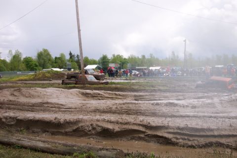 1978 Ford Bronco - A muddy track with multiple vehicles and spectators gathered in the background.