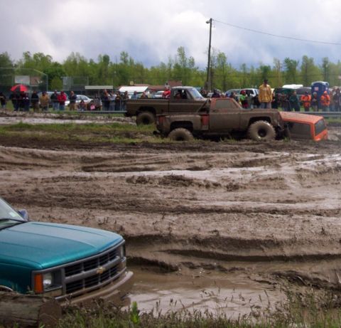 1978 Ford Bronco - Several trucks are stuck in a muddy track during a mud bogging event, with spectators watching from the sidelines.
