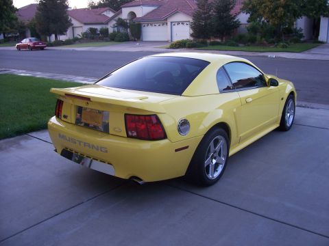 2002 Ford Mustang - Rear view of a yellow coupe with 'Mustang' badging.