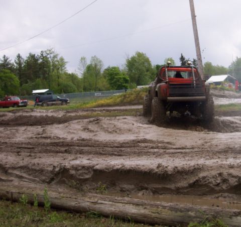 1978 Ford Bronco - Multiple trucks navigate a challenging mud course under an overcast sky.