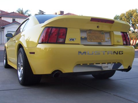 2002 Ford Mustang - Rear view of a yellow 2002 Ford Mustang GT, showing its distinctive taillights and spoiler.
