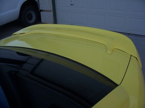 2002 Ford Mustang - A yellow car's spoiler and roof are visible, with a white truck parked nearby.