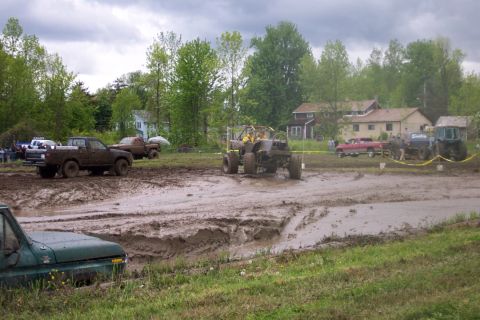 1978 Ford Bronco - Multiple vehicles are participating in a mud bogging event on a cloudy day.