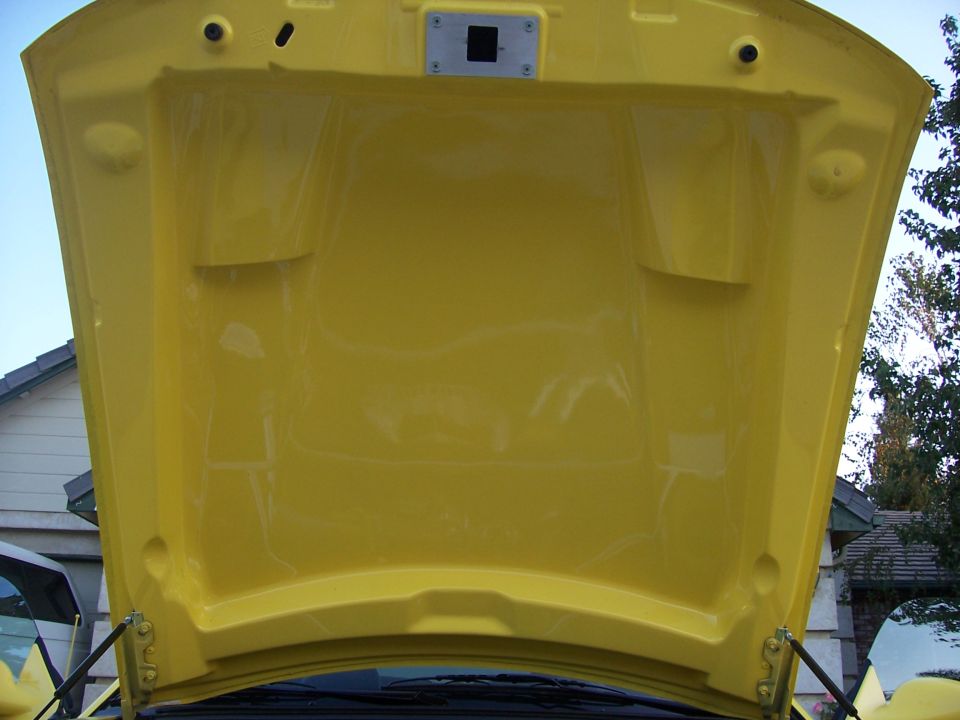 yellow underhood of a car, open to reveal the underside of the hood