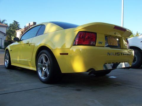 2002 Ford Mustang - Rear view of a yellow 2002 Ford Mustang GT, its distinctive spoiler and GT badging.