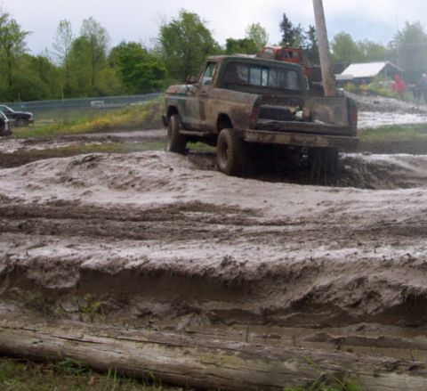 1978 Ford Bronco - A pickup truck navigates a challenging muddy terrain, with another vehicle in the background.