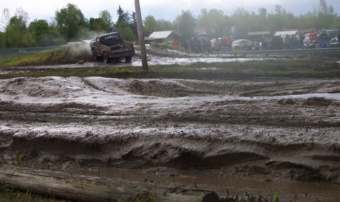 1978 Ford Bronco - A truck navigates a muddy track during an event, with onlookers gathered nearby.