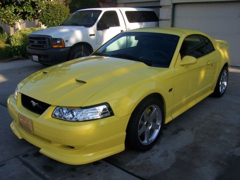 2002 Ford Mustang - Yellow 2002 Ford Mustang coupe with aftermarket body kit and wheels.