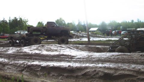 1978 Ford Bronco - Multiple lifted trucks and a buggy participate in a mud bogging event, with spectators in the background.