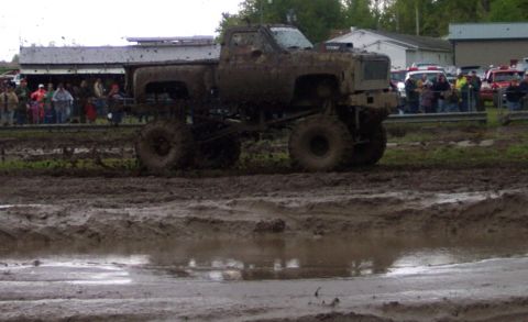 1978 Ford Bronco - A heavily modified pickup truck navigates a challenging mud course with onlookers present.