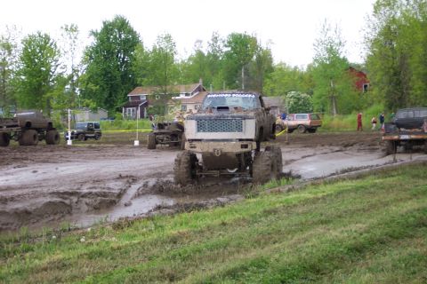 1978 Ford Bronco - Several lifted trucks participate in a mud bogging event on a wet, muddy track.